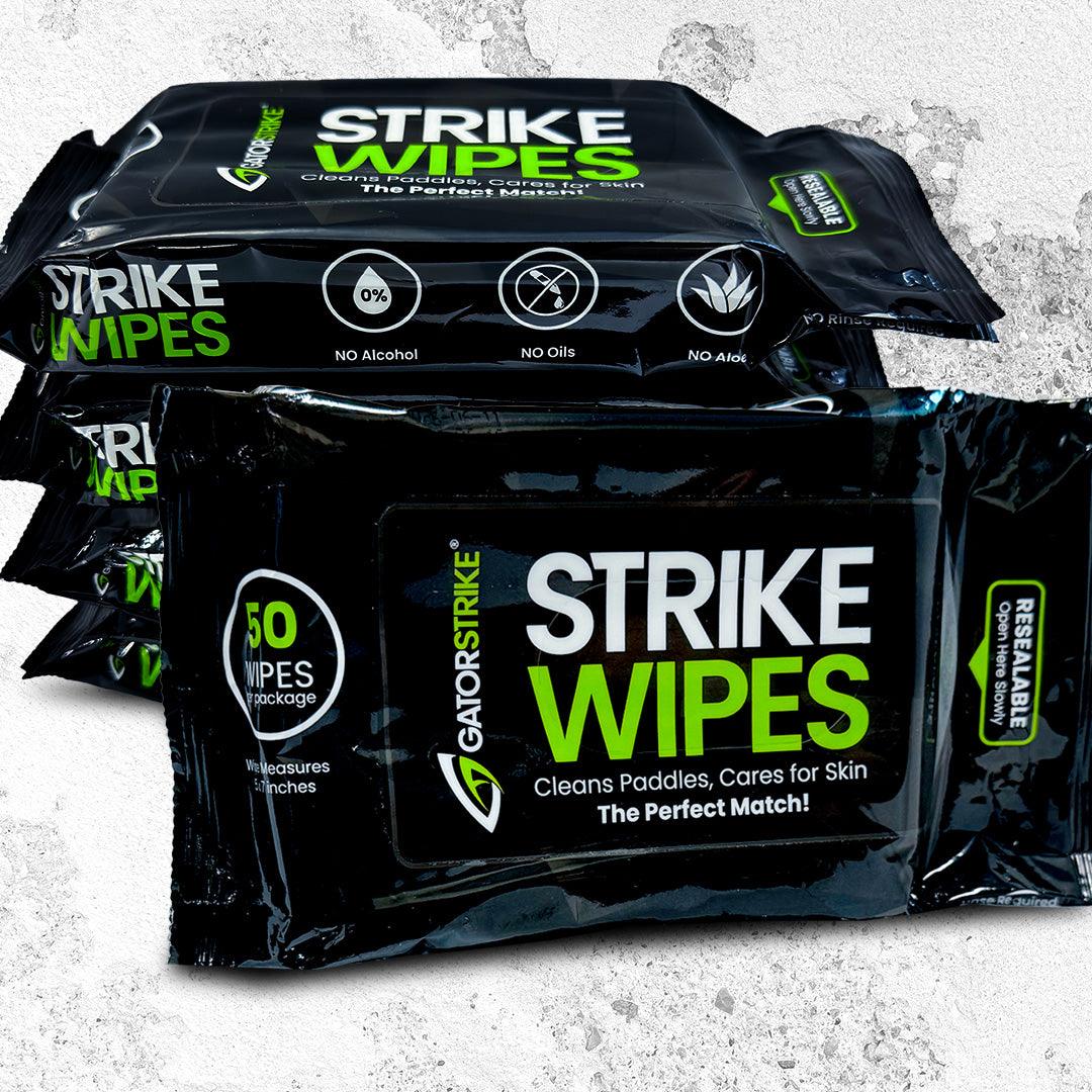 Three packs of GATORSTRIKE™ Paddle Wipes sit against a gray textured background. The black packaging with green and white text showcases these non-toxic, alcohol-free, resealable wipes—ideal for cleaning your paddle.