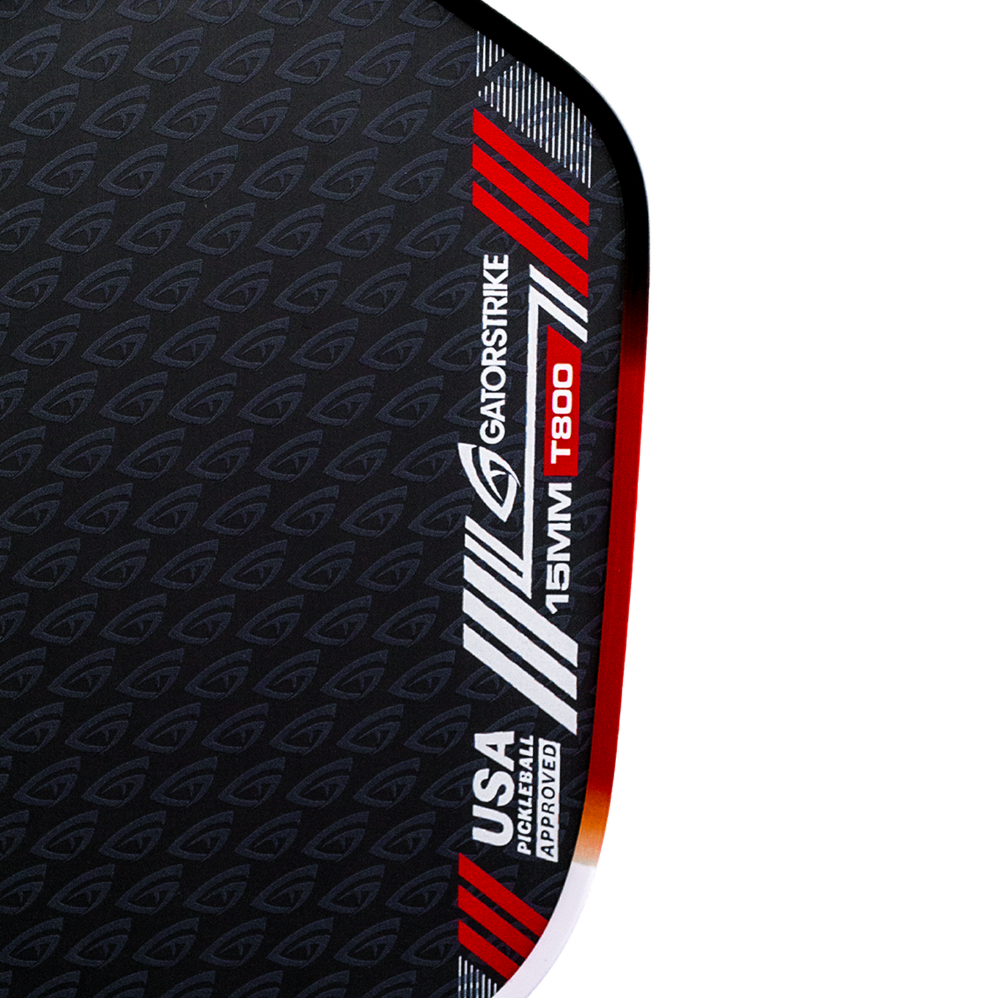 Close-up of a black textured GATORSTRIKE surface with diagonal gray logos. Red, white, and silver edge stripes read: "GATORSTRIKE, 15MM, T800, USA PICKLEBALL APPROVED." Curved orange border delivers explosive power and control.