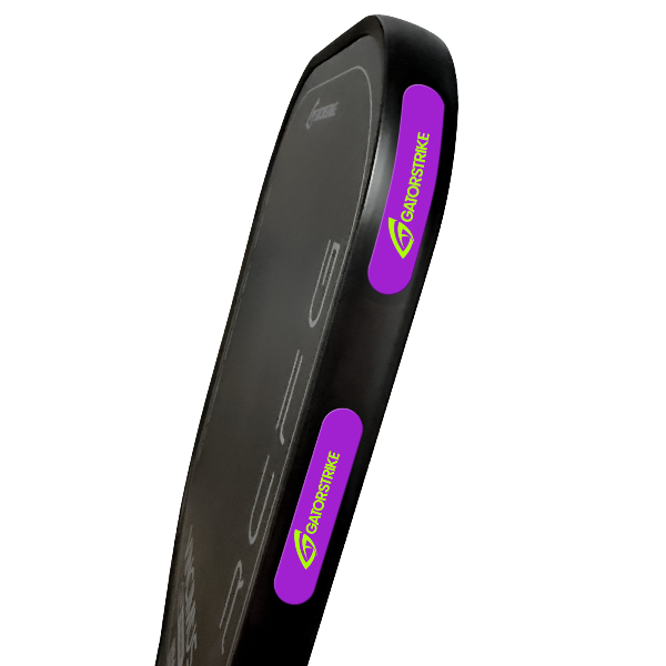 A close-up of a black rectangular striking pad, a useful pickleball accessory, featuring two purple and green GATORSTRIKE logos on the sides. The pad has rounded edges and a smooth surface, shown against a plain white background.